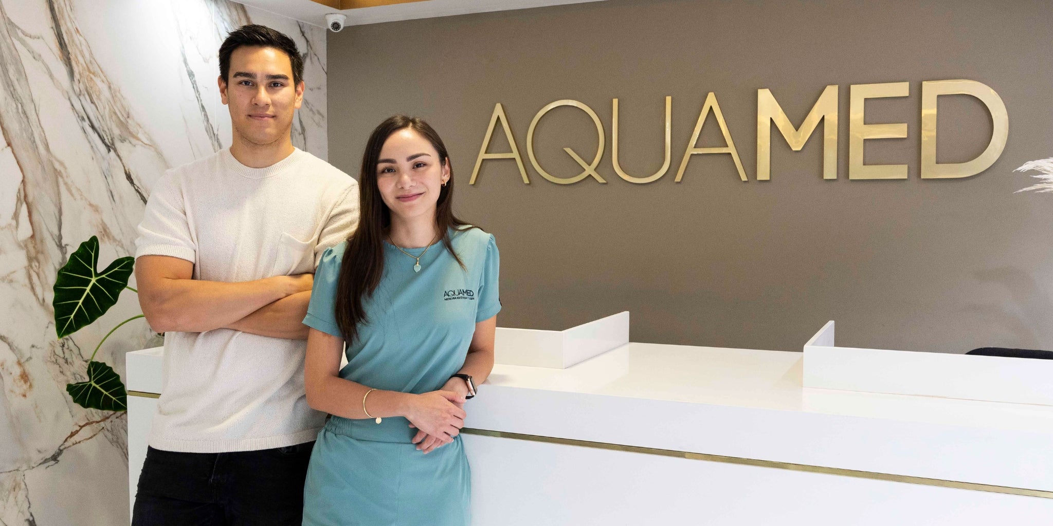 Two members of the Aquamed personel standing in front of a desk.
