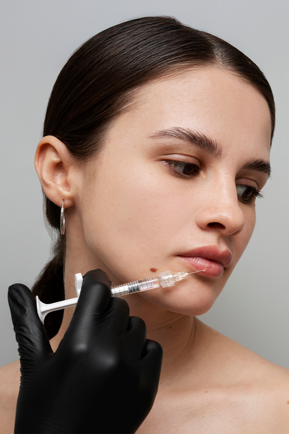 A woman receiving an injection on her bottom lip. 