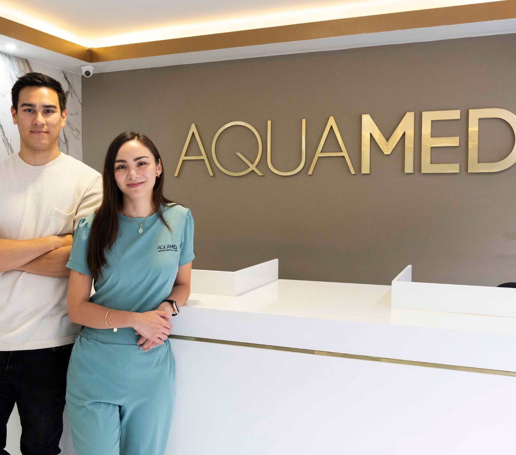 Two members of the Aquamed personel standing in front of a desk.