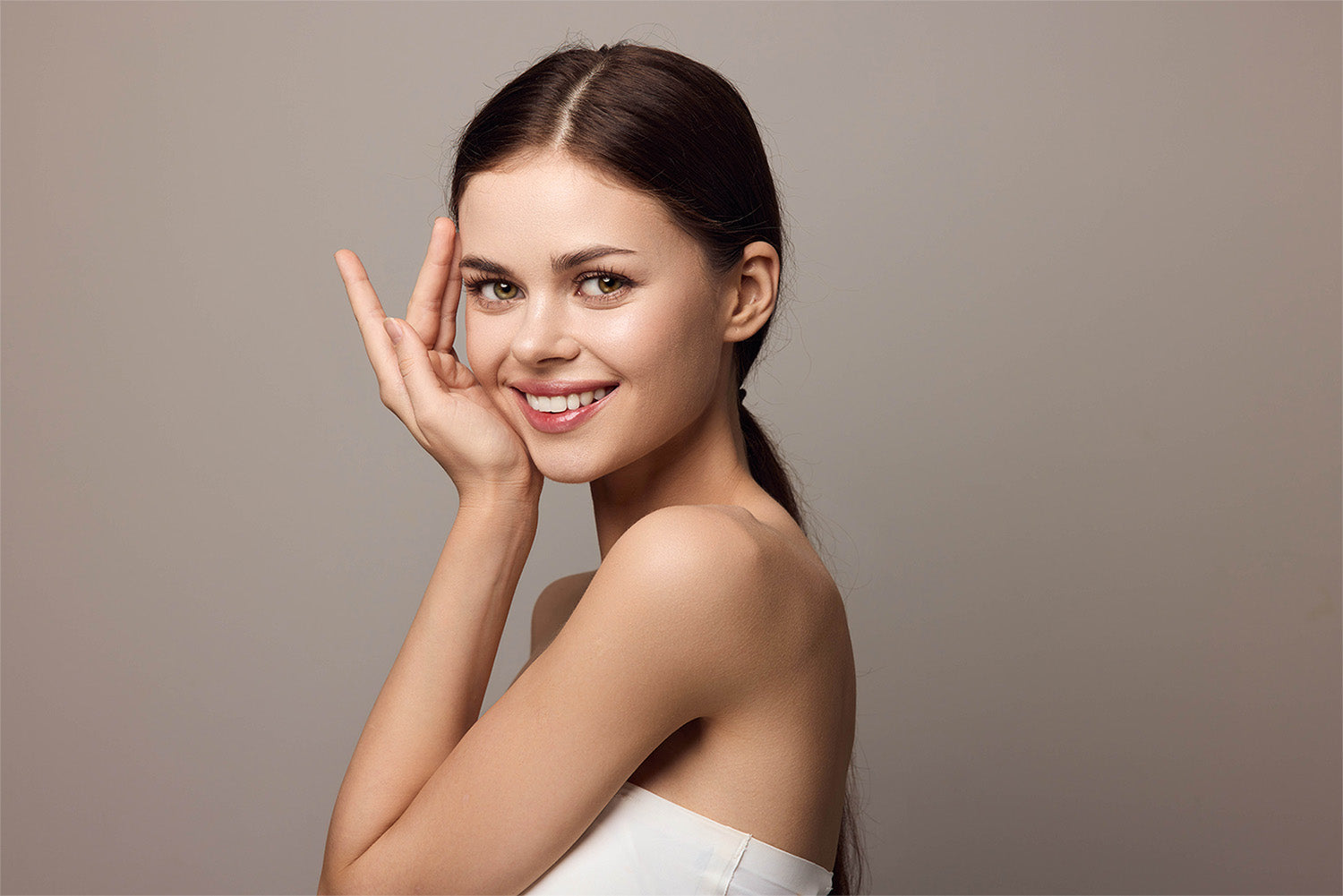 A woman smiling looking sideways at the camera.